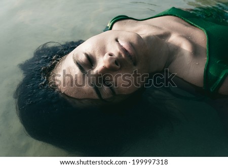Female Model Submerged Up To Her Face in Water with eyes closed.