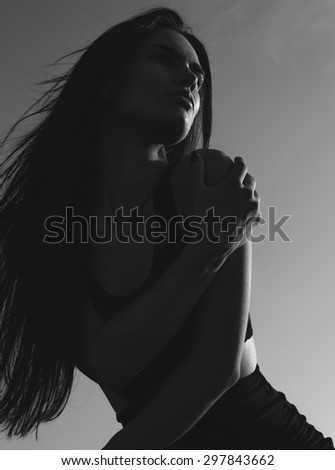 Close up youthful young long-haired woman hugging herself while looking Into the distance