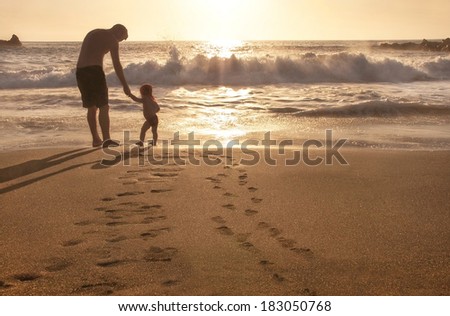 Family vacation. Happy resting baby and father  are on the beach at sunset near ocean. Relaxing family. Summer travel concept. Outdoor. Copy space.