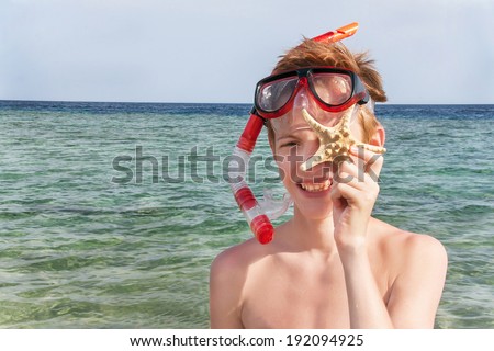 Caucasian boy standing at the summer beach with snorkeling mask. Happy teenager is smiling  with  starfish (shellfish) in sunny summer day. Copyspace, close up, outdoor (Sharm El Sheikh, Egypt).