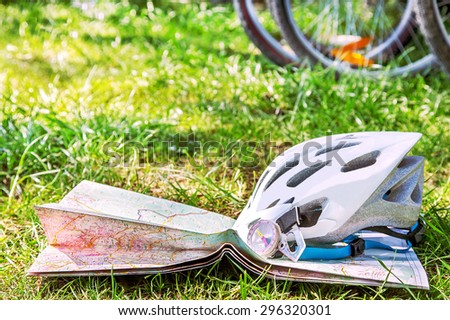 Helmet mountain biking, map, compass are on the grass background (texture) with bikes (bicycles). The empty pattern for message. Copy space. Summer vacations (travel), freedom, adventure  concept.
