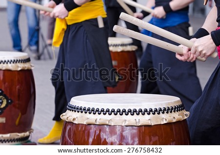 Group of japanese musicians are playing on traditional japanese percussion instrument Taiko or Wadaiko drums. The drumsticks are in the hands.