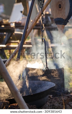 Sunlit steaming pot with food heated on the fire