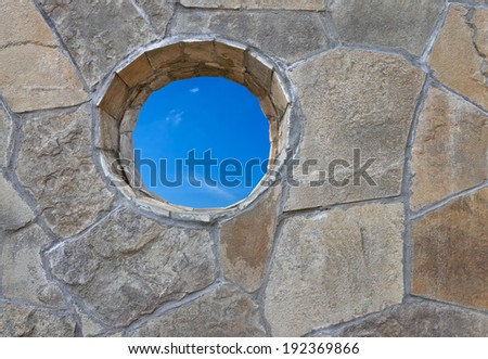 Stone wall with the round hole through which one can see the sky