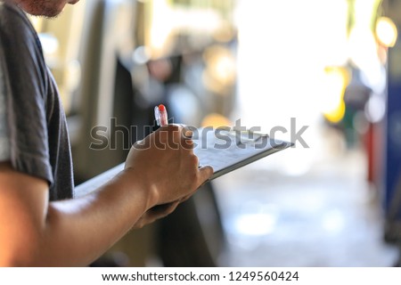 Mechanic holding clipboard with checking truck in service center,Preforming a pre-trip inspection on a truck,preventive maintenance,spot focus Imagine de stoc © 