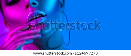 High Fashion model metallic silver lips woman in colorful bright neon blue and purple lights posing in studio, beautiful girl, trendy glowing make-up, colorful make up. Glitter Vivid neon makeup Foto stock © 