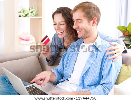 Online Shopping.Happy Smiling Couple Using Credit Card to Internet Shop on-line. Young couple with Laptop Computer and Credit Card buying online. Christmas and New Year Gifts. e-shopping . ecommerce