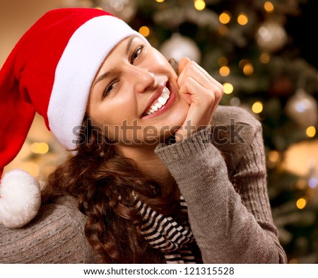 Christmas Woman in Santa Hat.Happy Smiling Girl Celebrating New Year at Home. Christmas Tree