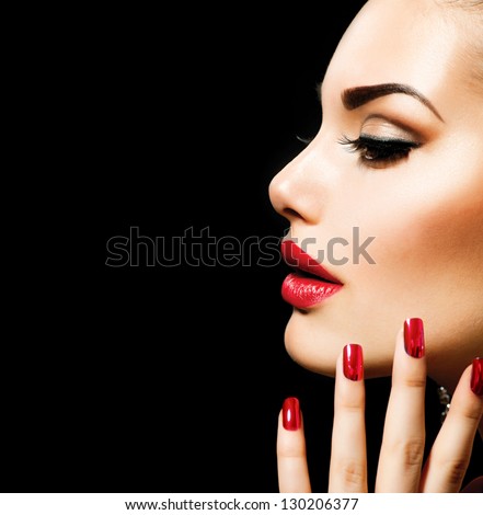 Beauty Woman with Perfect Makeup. Beautiful Professional Holiday Make-up. Red Lips and Nails. Beauty Girl\'s Face isolated on Black background. Glamorous Woman