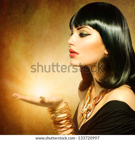 Egyptian Style Woman with Magic Light in Her Hand. Golden Jewels. Egypt Styled Makeup. Gold Light. Jewellery