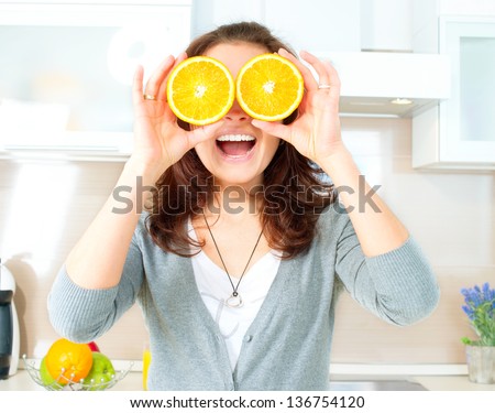 Young and Healthy Funny Woman with Orange over Eyes in the Kitchen. Diet and Healthy Eating Concept