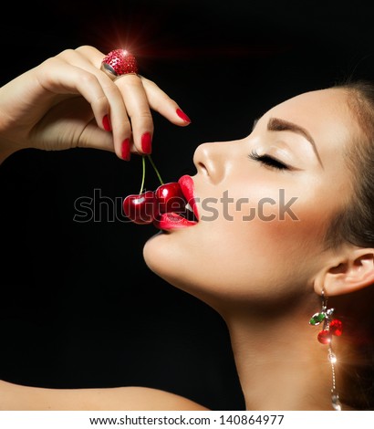 Sexy Woman Eating Cherry. Sensual Red Lips. Red Manicure, Lipstick and Ring. Desire. Sexy red Lips with Cherries isolated on Black