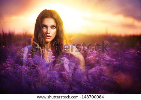 Beauty Girl Portrait. Sensual Woman Lying on a Meadow with Violet Flowers. Beautiful Woman Enjoing Nature