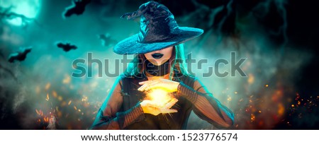 Halloween Witch girl with making witchcraft, magic in her hands, spells. Beautiful young woman in witches hat conjuring. Spooky dark magic forest background. Magician. Wide Halloween party art design