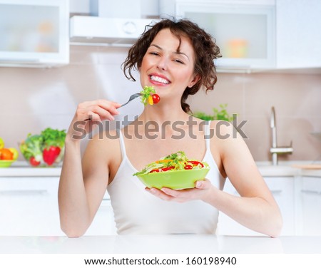 Diet. Beautiful Young Woman Eating Vegetable Salad in the Kitchen. Dieting concept. Healthy Vegan Food. Healthy Smiling Girl with Bowl of Salad and Fork. Weight Loss. Vegetarian Food