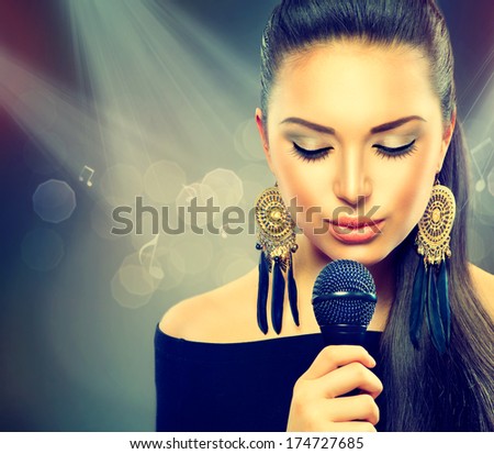 Beautiful Singing Girl. Beauty Woman with Microphone over Blinking bokeh night background. Glamour Model Singer. Karaoke song