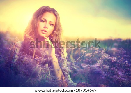 Beauty Girl Portrait. Sensual Woman Lying on a Meadow with Violet Flowers. Beautiful Woman Enjoying Nature. Romantic beauty in fantasy lavender field