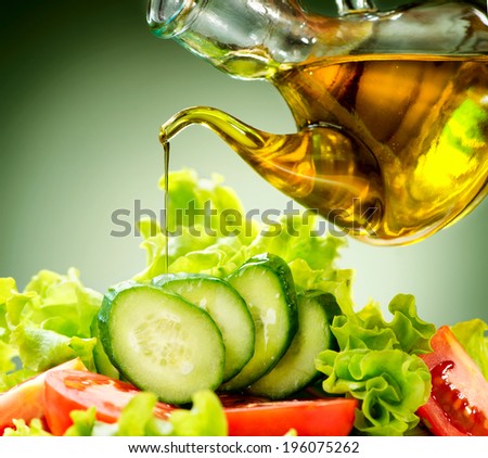 Healthy Vegetable Salad with Olive oil dressing. Pouring Olive oil. Healthy vegetarian food. Vegan. Diet, dieting concept. Lettuce, tomatoes, cucumbers. Organic bio food