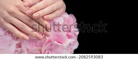Beautiful Healthy nails. Manicure, Beautiful Woman's hands, Spa. Female hands with beautiful natural pink french elegant manicure on hydrangea flower. Skincare. Salon, treatment. Isolated on black Foto stock © 