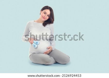 Pregnant Woman touching her belly. Pregnant middle aged mother's hands caressing her tummy. Healthy Pregnancy concept, Sitting Gravid female on blue background, full length portrait Imagine de stoc © 