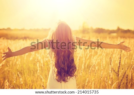 Autumn Girl enjoying nature on the field. Beauty Girl Outdoors raising hands in sunlight rays. Beautiful Teenage Model girl in white dress running on the Field, Sun Light. Glow Sun. Free Happy Woman