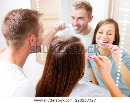 Beauty Young couple in the bathroom brushing teeth together. Happy family cleaning teeth with a tooth brush, looking at their white teeth at the mirror, enjoying their smile. Defocused reflection