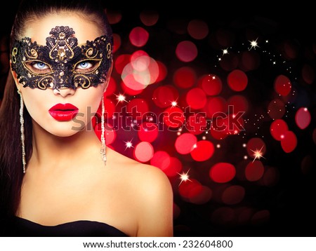Sexy model woman in venetian masquerade carnival mask at party over holiday glowing red background. Christmas and New Year celebration. Glamour lady