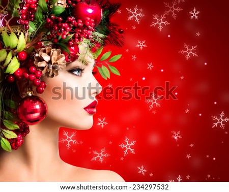 Christmas Winter Woman. Beautiful New Year and Christmas Tree Holiday Hairstyle and Make up. Beauty Fashion Model Girl over holiday red Background. Creative Hair style decorated with Baubles. Makeup
