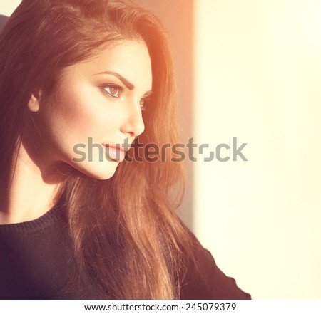 Sideways portrait of young beauty romantic girl looking away, close-up. Tender glance of beautiful brunette make-up woman in sun light.