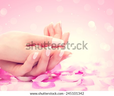 Manicure, Hands spa Beautiful feamle hands, soft skin, beautiful nails with pink rose flowers petals. Healthy Woman hands. Beauty salon. Beauty treatment. Beautiful nails with french manicure