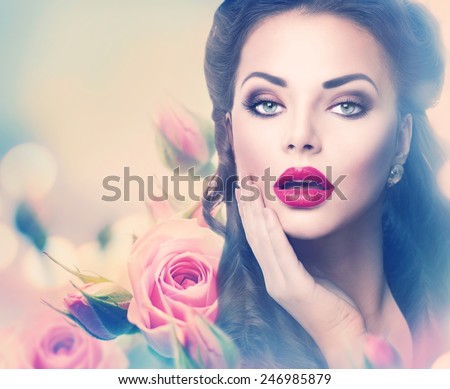 Retro woman portrait in beauty pink roses. Beautiful Vintage styled girl with flowers. Perfect makeup and hairstyle. Gorgeous model lady. Red Lips. Luxury Make up and Hair. Vogue Style