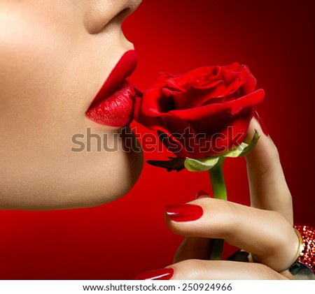 Beautiful Model woman kissing red rose flower. Red Lips, Nails and Rose. Beauty Girl. Makeup and Manicure. Sensual Mouth. Sexy Red Color Lips. St. Valentine\'s Day design. Part of Face