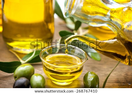 Olive Oil. Bottle pouring Virgin Olive Oil in a bowl close up. Olives and Healthy Olive oil being poured from glass bottle. Diet. Dieting concept. Healthy eating