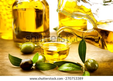 Olive Oil. Bottle pouring Virgin Olive Oil in a bowl close up. Olives and Healthy Olive oil being poured from glass bottle. Diet. Dieting concept. Healthy food