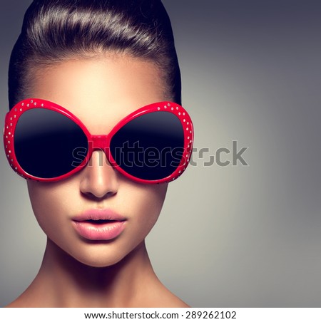 Beauty Fashion model brunette girl wearing stylish sunglasses. Beautiful Lady face. Sexy woman portrait over dark background