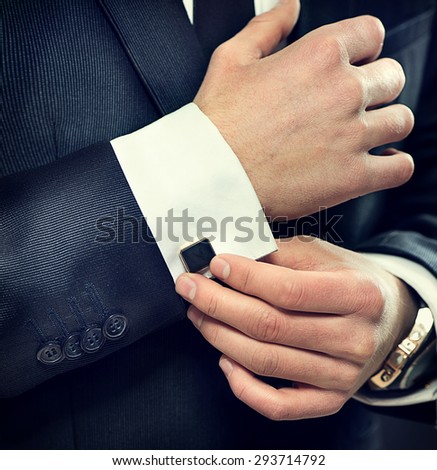 Close up of businessman wearing cufflinks. Elegant young fashion business man wearing suit