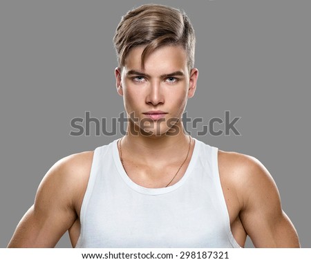 Handsome Athletic young man isolated on grey background. Muscular teenage guy portrait