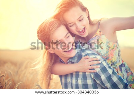 Beauty Couple having fun outdoors, relaxing on wheat field together. Happy girlfriend and boyfriend hugging, love concept. Beautiful Boy and Girl in love together
