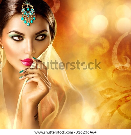 Beautiful Arabic girl portrait. Beauty young Arabian woman with menhdi, perfect make-up and accessories hiding her face behind a veil. Indian Bride. Arab Traditions and culture concept