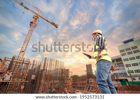 Civil engineer or architect with hardhat on construction site checking schedule on tablet computer.Foreman worker with tablet computer wear construction uniform with structure site work background Foto stock © 