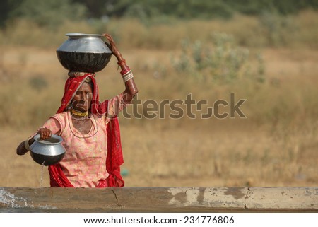 PUSHKAR,INDIA - November 3,2014 : Unidentified women draw water form the well and take it to her tent in desert near Pushkar,India