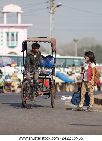 AGRA,INDIA - March 25,2013 : Unidentified rickshaw driver and a modern indian young woman are in the streets of Agra.Rickshaw ( tuk tuk ) is one of the most important transportation vehicles in India.
