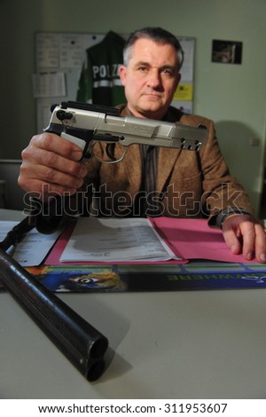 Worms, Germany - November 26, 2009 - Officer shows guns and ammunition confiscated during a raid
