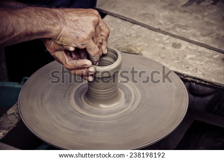 hands of a man, creating an earthen jar on the circle