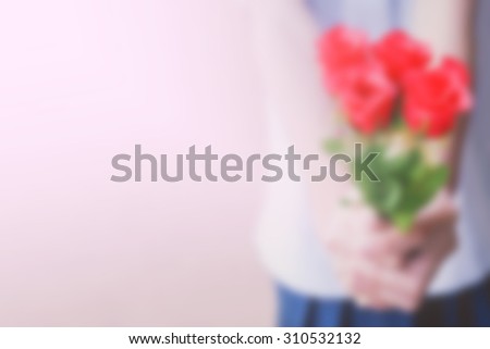 Blurred Hand holding bouquet a red roses.