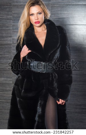 Fashion beautiful blonde woman posing in fur coat. Winter Girl Model in Luxury clothes and furry collar on gray background.
