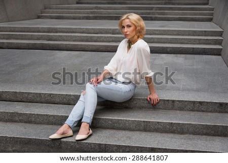 Outdoor summer fashion stunning portrait on pretty young blonde sexy woman dressed in a white shirt and torn jeans having fun in the street.