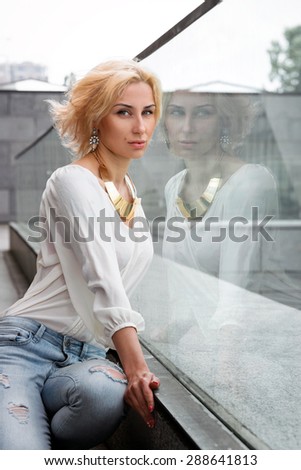 Outdoor summer fashion stunning portrait on pretty young blonde sexy woman dressed in a white shirt and torn jeans having fun in the street.