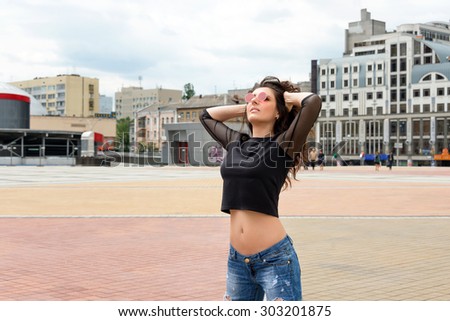 Glamorous young brunette woman in round red sunglasses having fun in the city