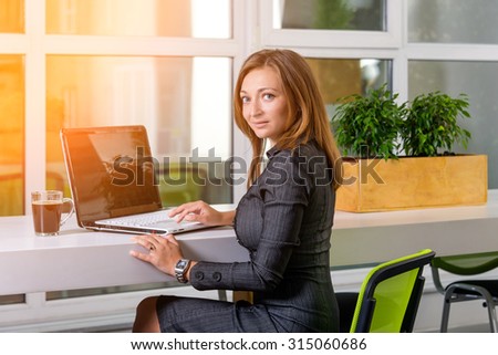 Business, technology and green office concept - young successful businesswoman with laptop computer at office. Woman using tablet computer or having a coffee break